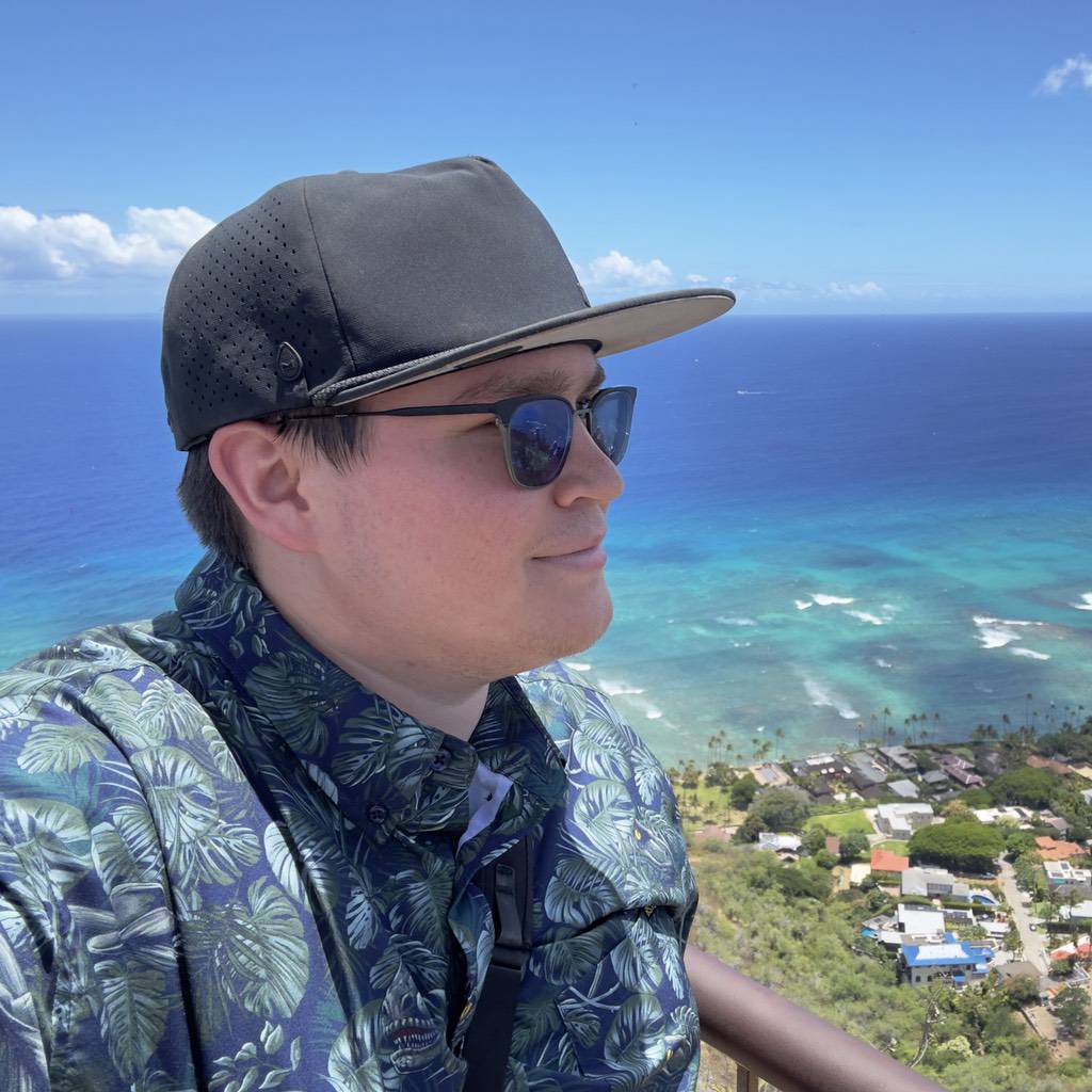 Photo of Blaine Miller with an oceanic island scene behind him